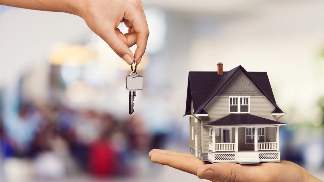 hand-giving-metal-house-keys-mini-house